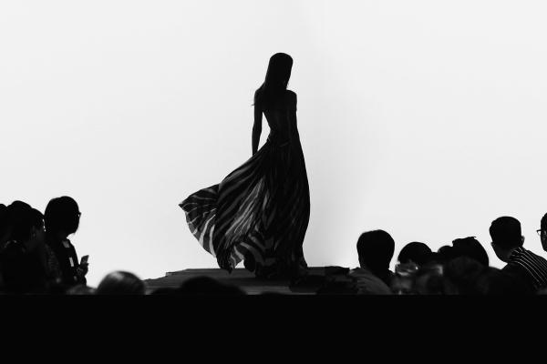Silhouette of a fashion model on a runway with large audience