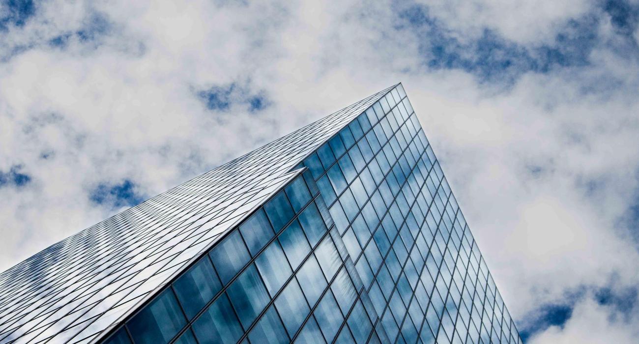 Glass building reflects a cloudy blue sky